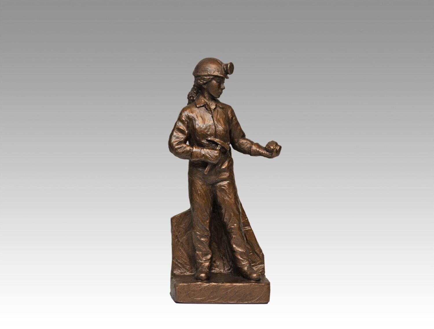 Gallery, Chipping Away, $225 CAD, Metal Infused, 10” H, Edition 80, Mining Sculpture of a Woman Miner holding a chipping hammer and rock with headframe in back, Sculptor Tyler Fauvelle