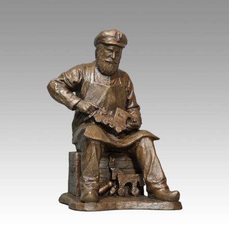 Gallery, The Toymaker, $575 CAD, Metal Infused, 14 ¾”H x 9"W, Edition 45, Sculpture of a Toymaker sitting on a crate making a wooden toy train with toys at his feet, Sculptor Tyler Fauvelle